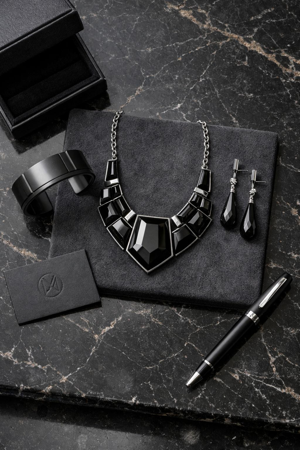 Gothic business casual jewelry featuring jet black onyx necklace and titanium cuff on marble