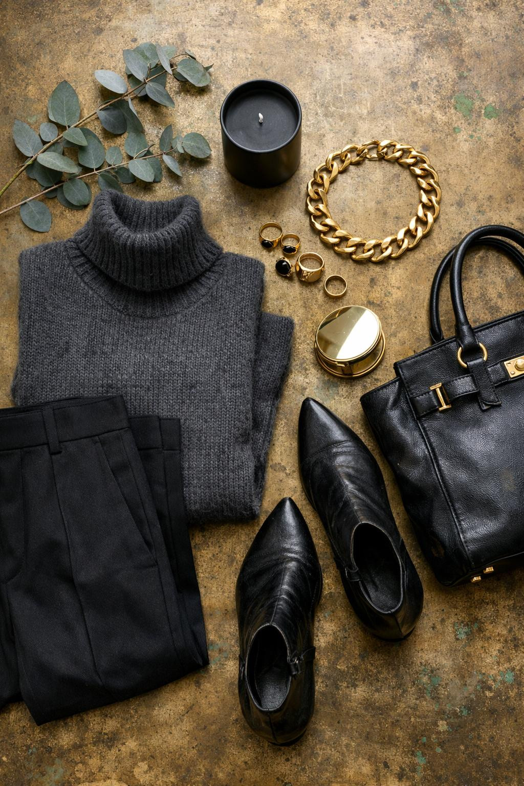 Gothic business casual flat lay featuring charcoal cashmere and chunky gold jewelry on brass