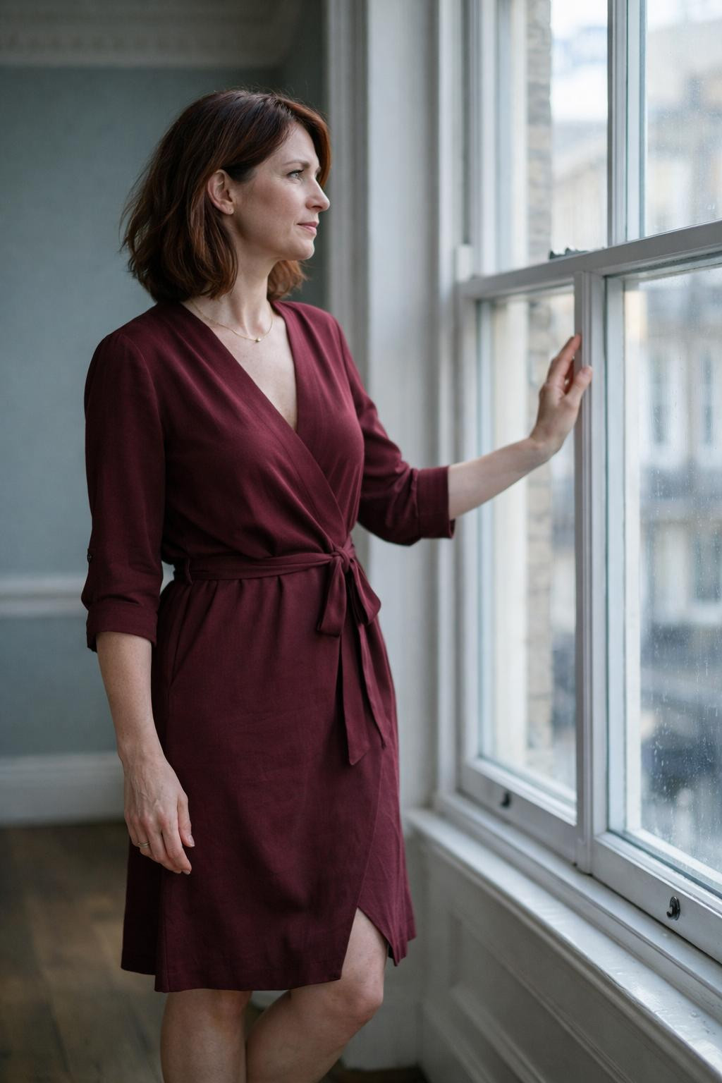 Business professional outfits with burgundy wrap dress by window