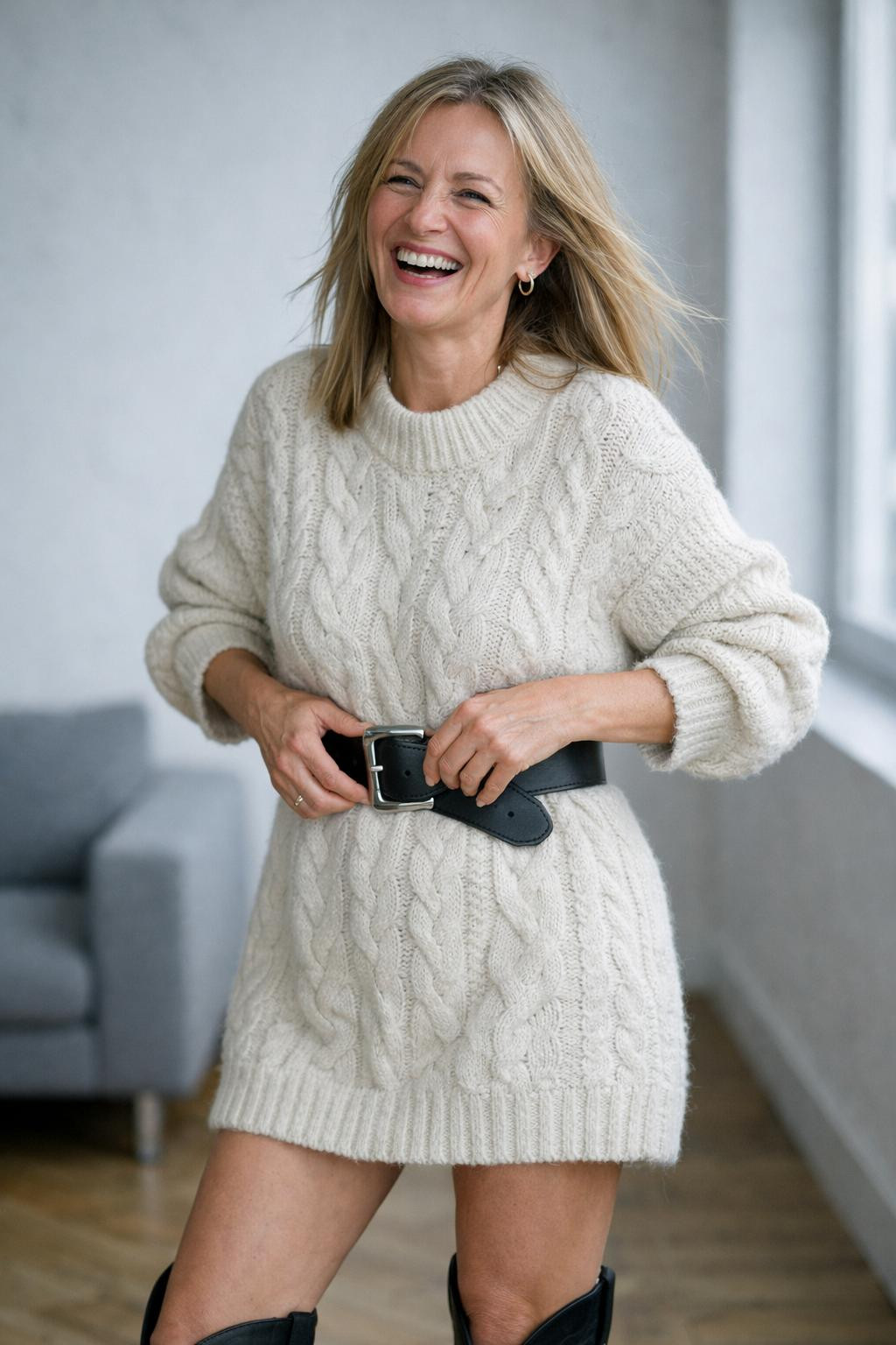 Black cowboy boots outfit with oversized chunky cream cable-knit sweater dress and belt