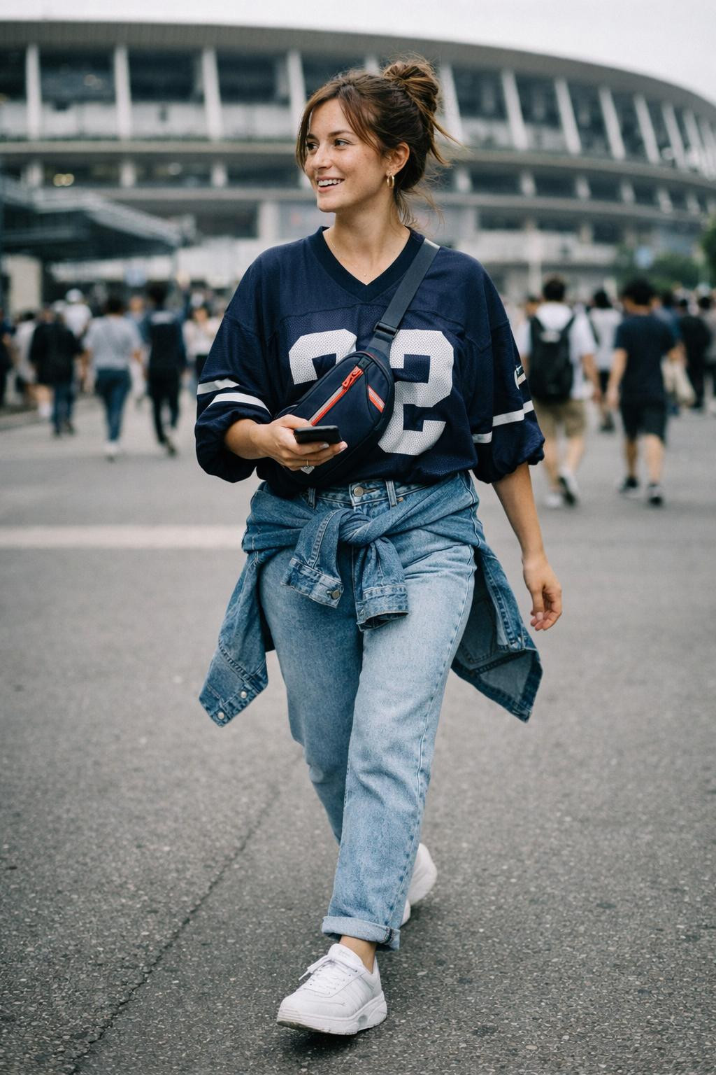 Football game outfit with oversized cream jersey and denim jacket tied at waist