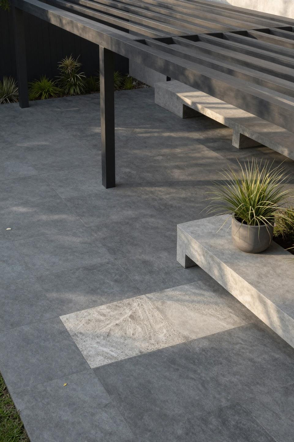 Modern stamped concrete patio with precise geometric slate grid and steel pergola