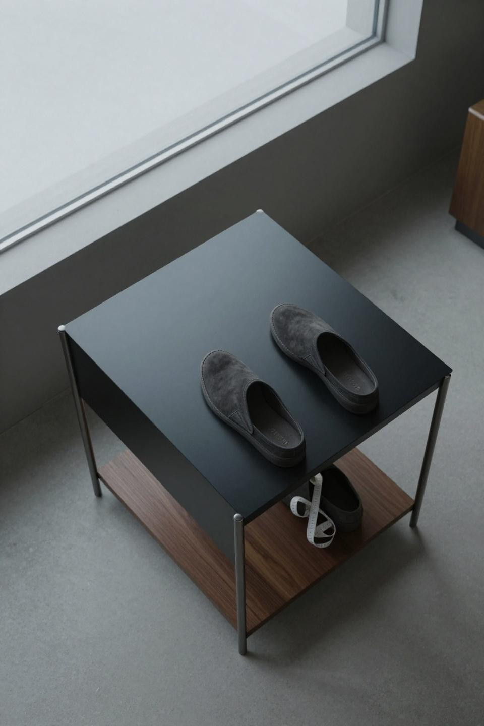 Shoe rack bench with sculptural matte black metal storage island and deep walnut base