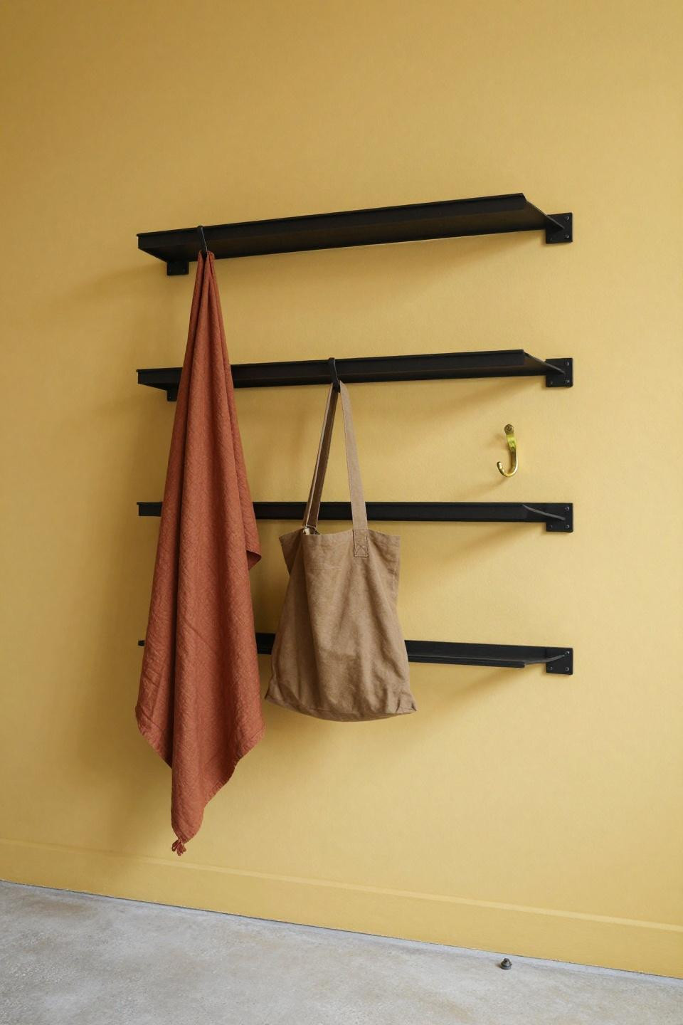 Small drop zone ideas with blackened steel coat rack on mustard wall