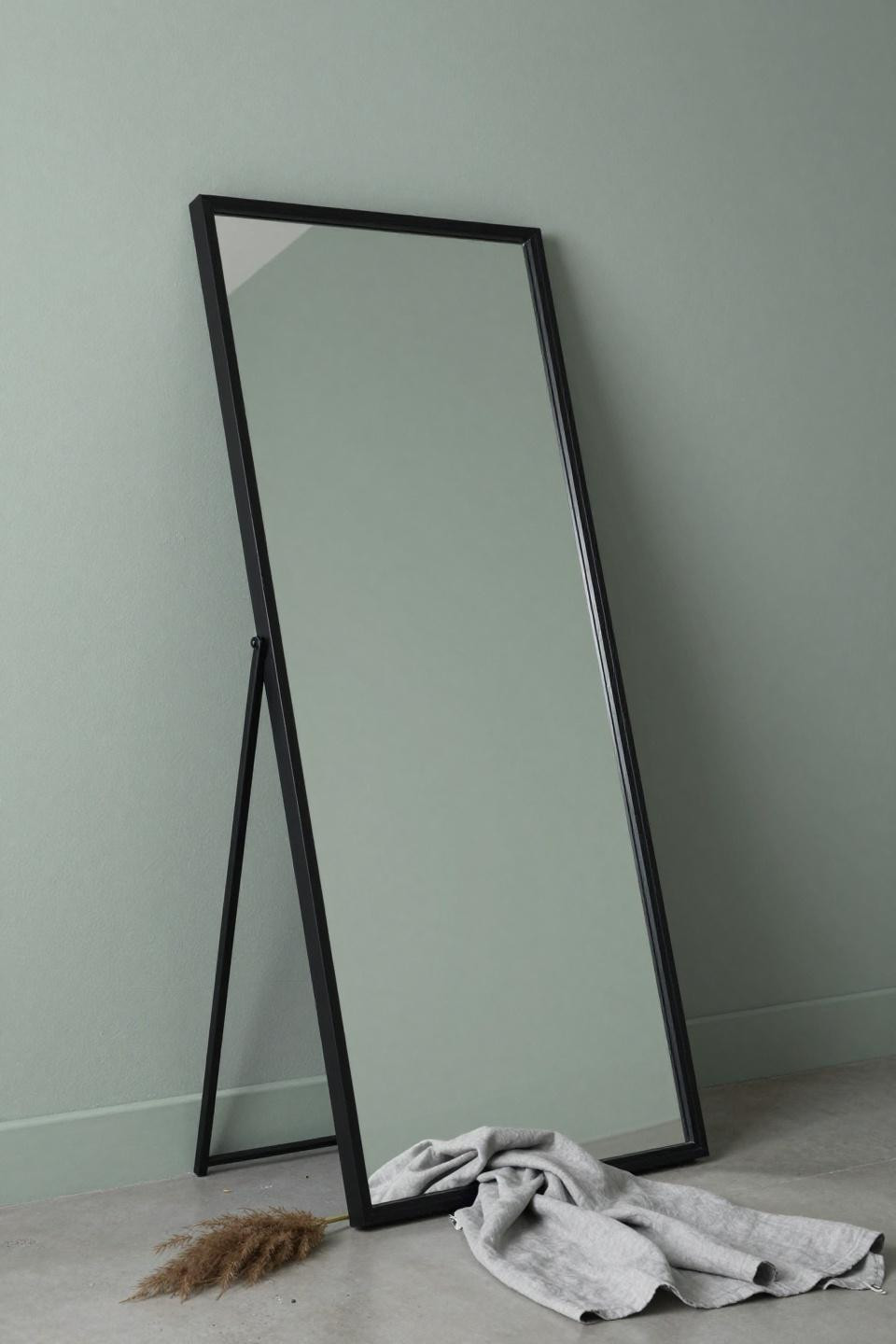 Mirror decorating ideas with large frameless rectangular mirror tilted against sage green wall