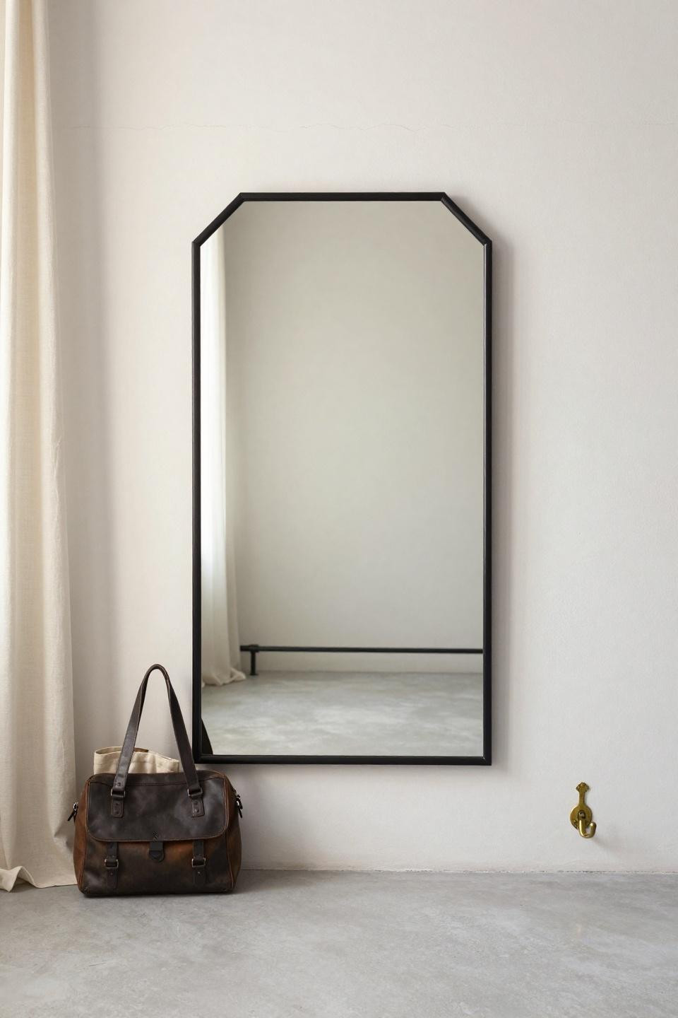 Aesthetic mirror with large octagonal matte black metal frame centered on white plaster wall