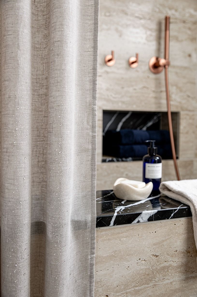 Mix a linen shower curtain into a light travertine bathroom
